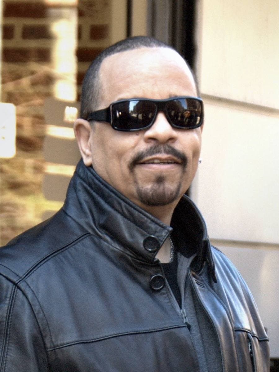 A man in a dark coat and cap on a city street
