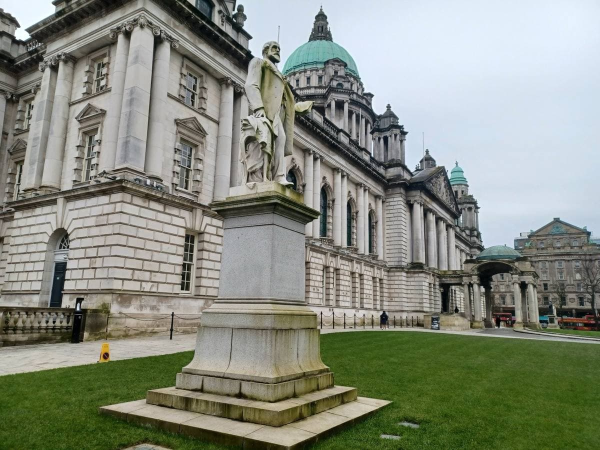 A white Portland stone hall with a green copper dome and corner towers behind lawns