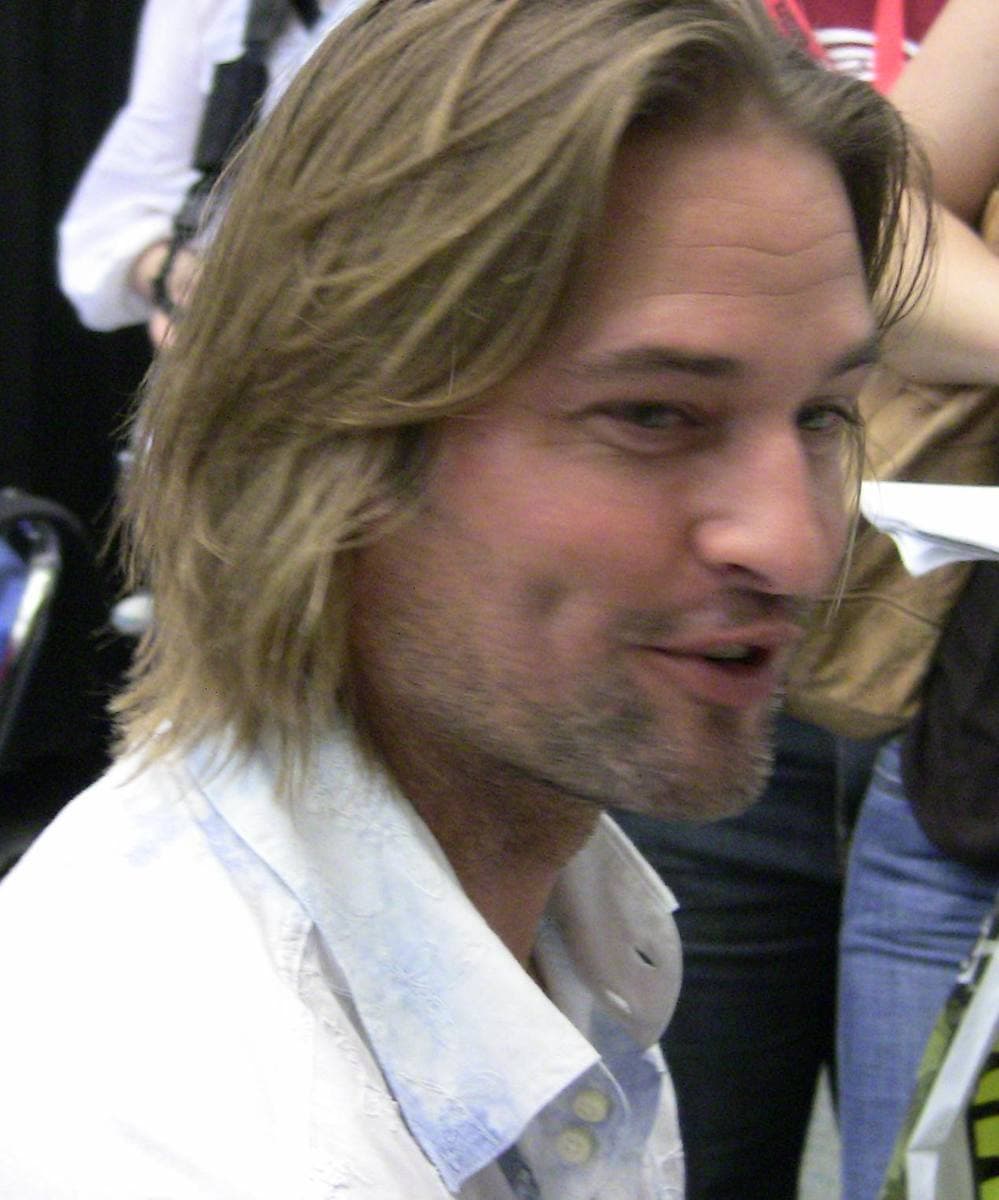 Josh Holloway with shoulder-length hair and stubble, in a white shirt