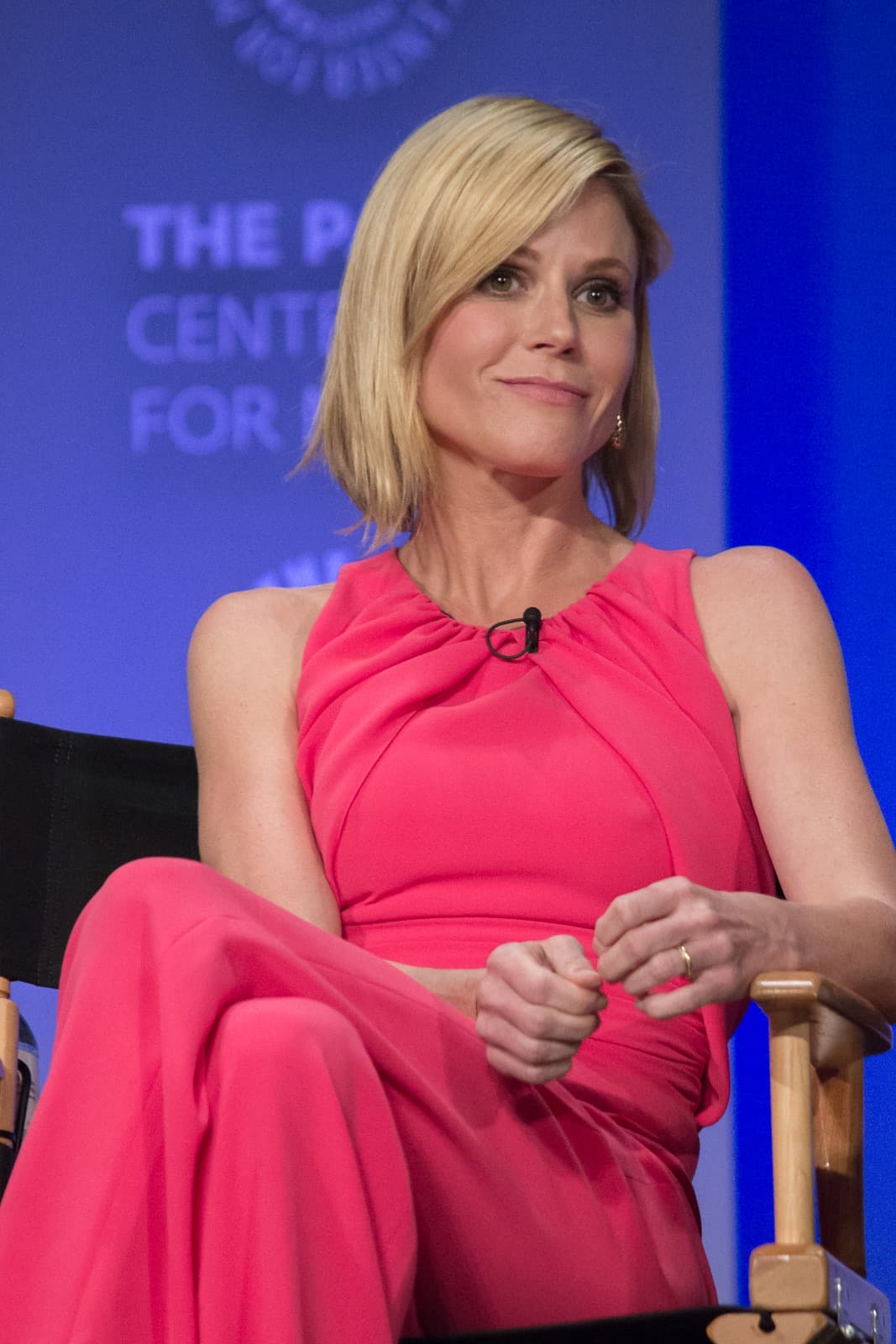 Julie Bowen in a pink dress, seated on a panel stage