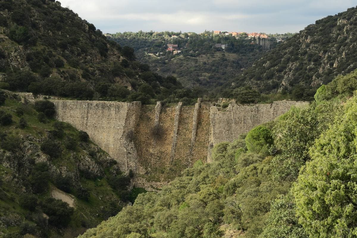 A huge ruined stone dam wall in a rocky river valley
