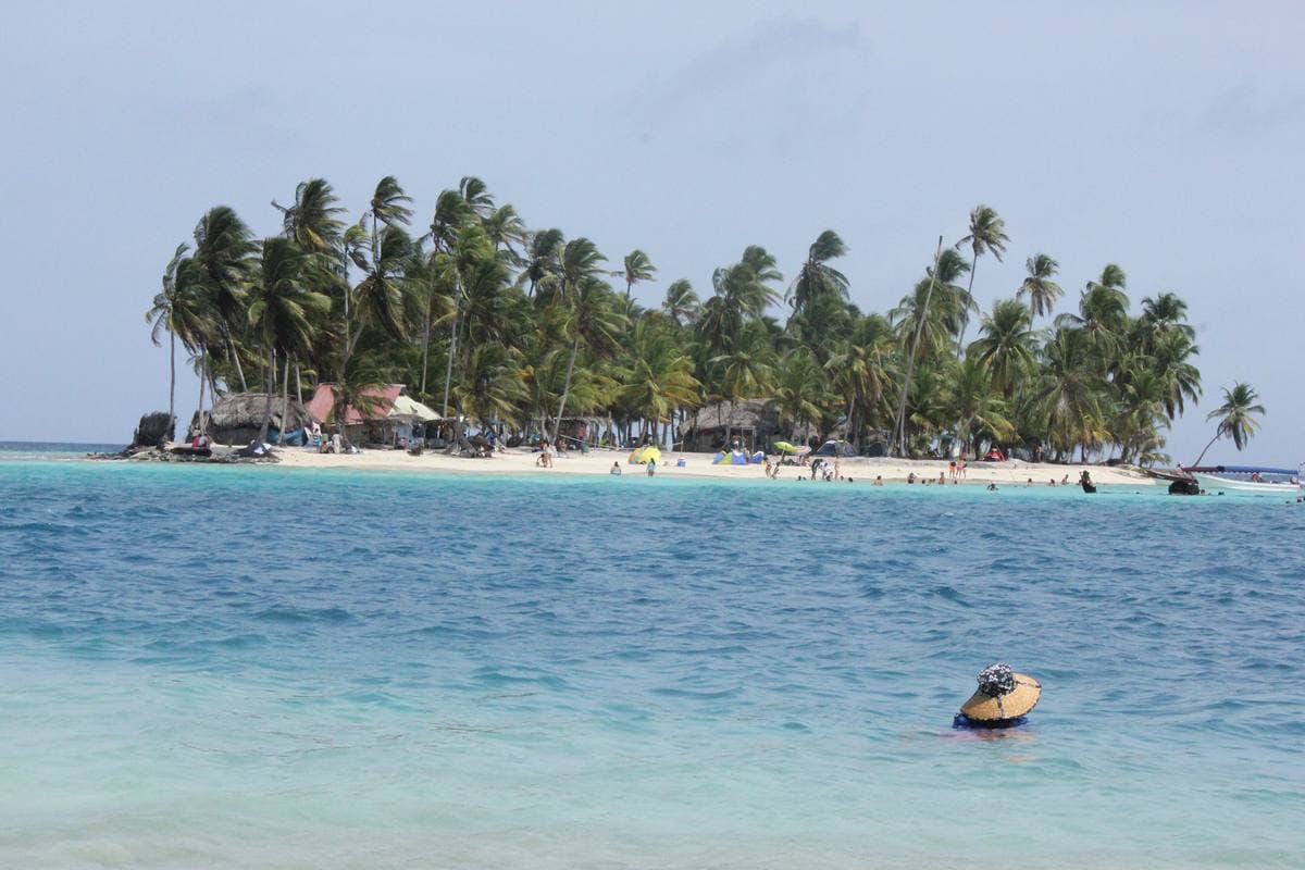 A small palm island ringed by white sand and turquoise water