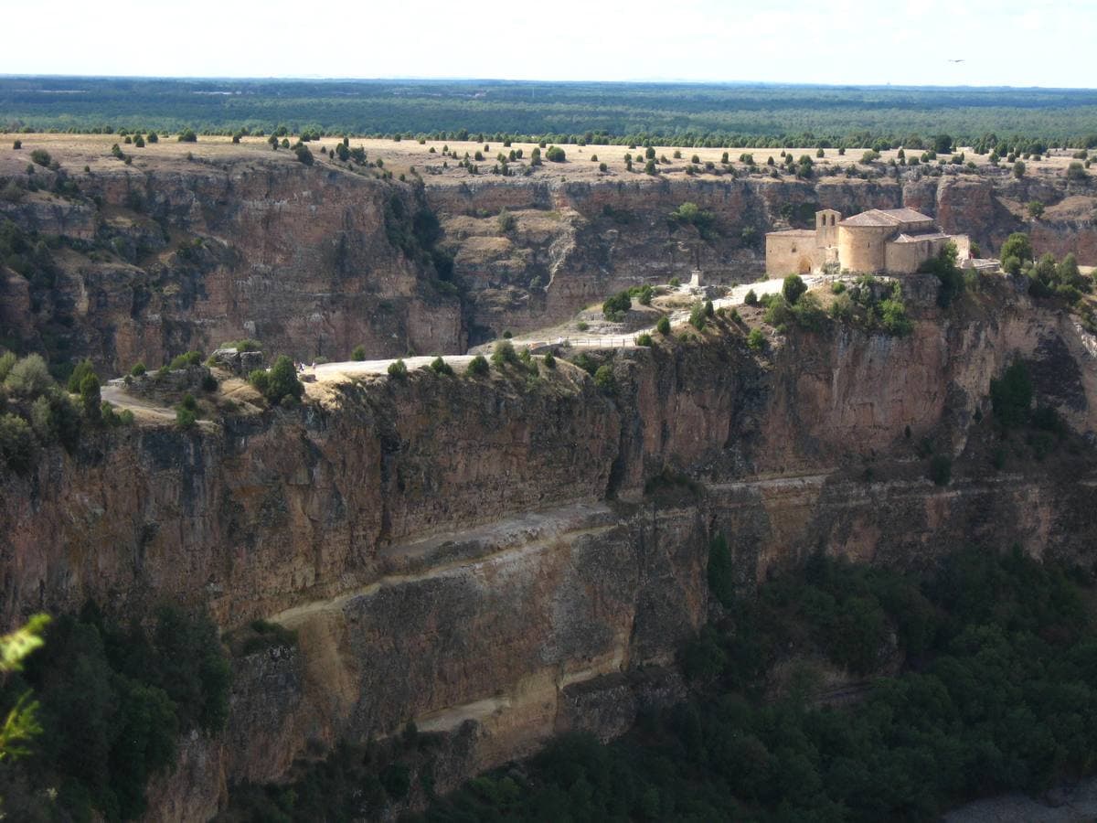 A small stone church on a cliff edge above a river gorge