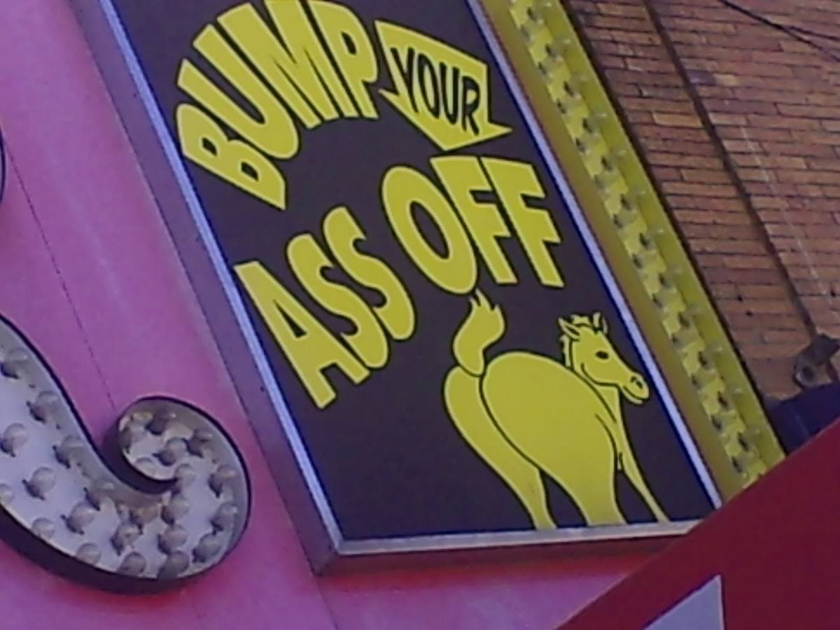 A yellow and pink sign with a cartoon horse and a cheeky slogan