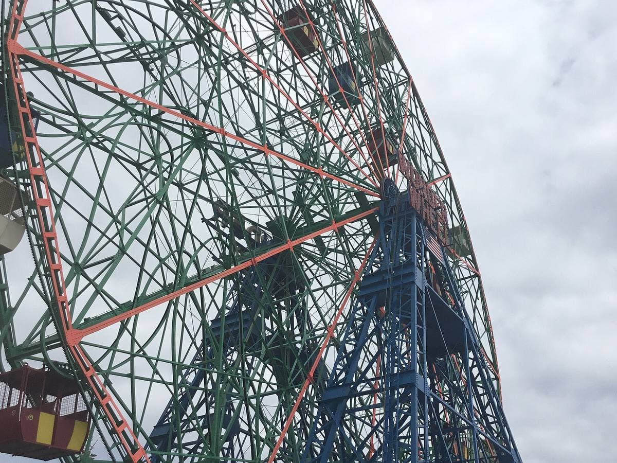 The green steel spokes of the Wonder Wheel and a passenger car, seen from below