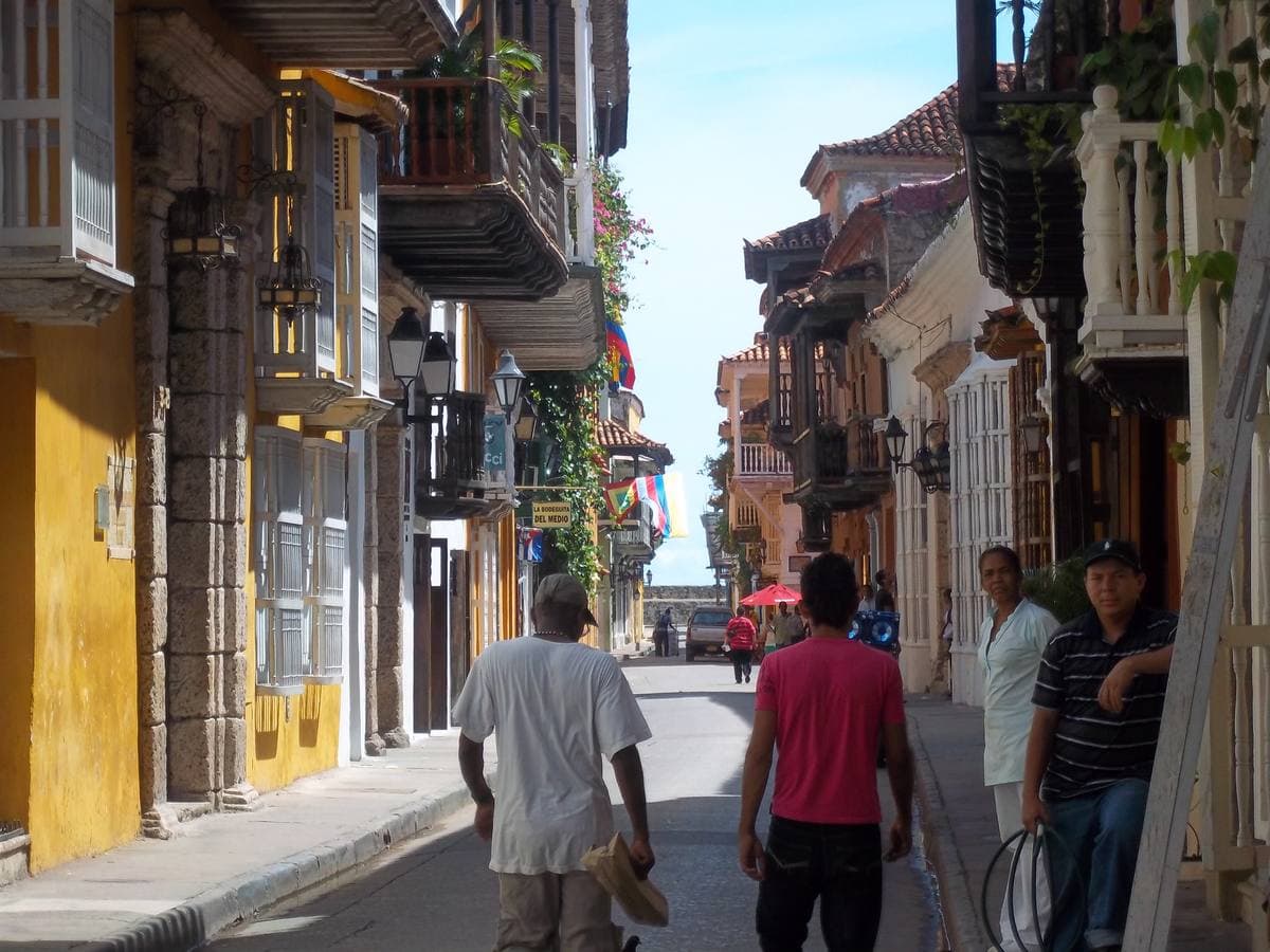 A narrow street of brightly painted colonial houses with wooden balconies and flowers