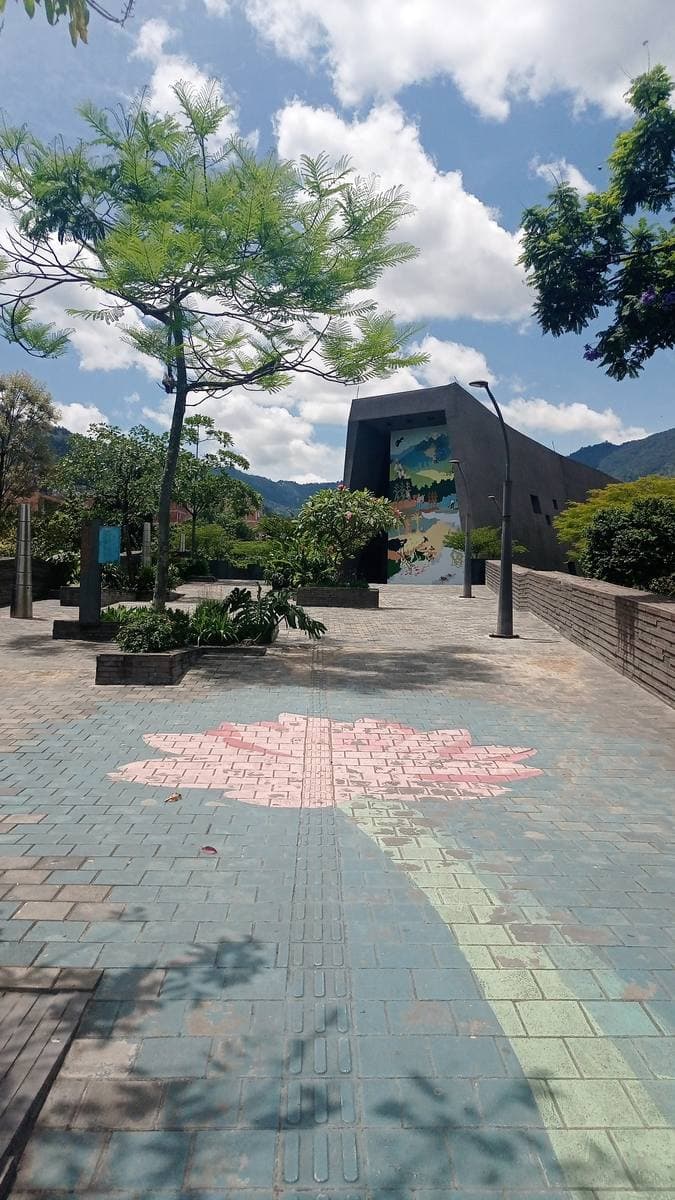 A pink flower painted on the paving outside a modern museum among trees