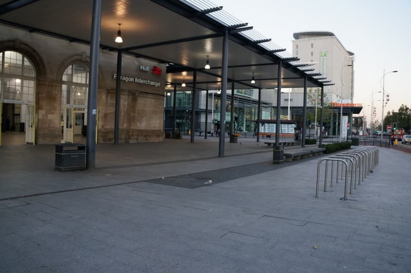 A station forecourt under a glass canopy with the Paragon Interchange sign