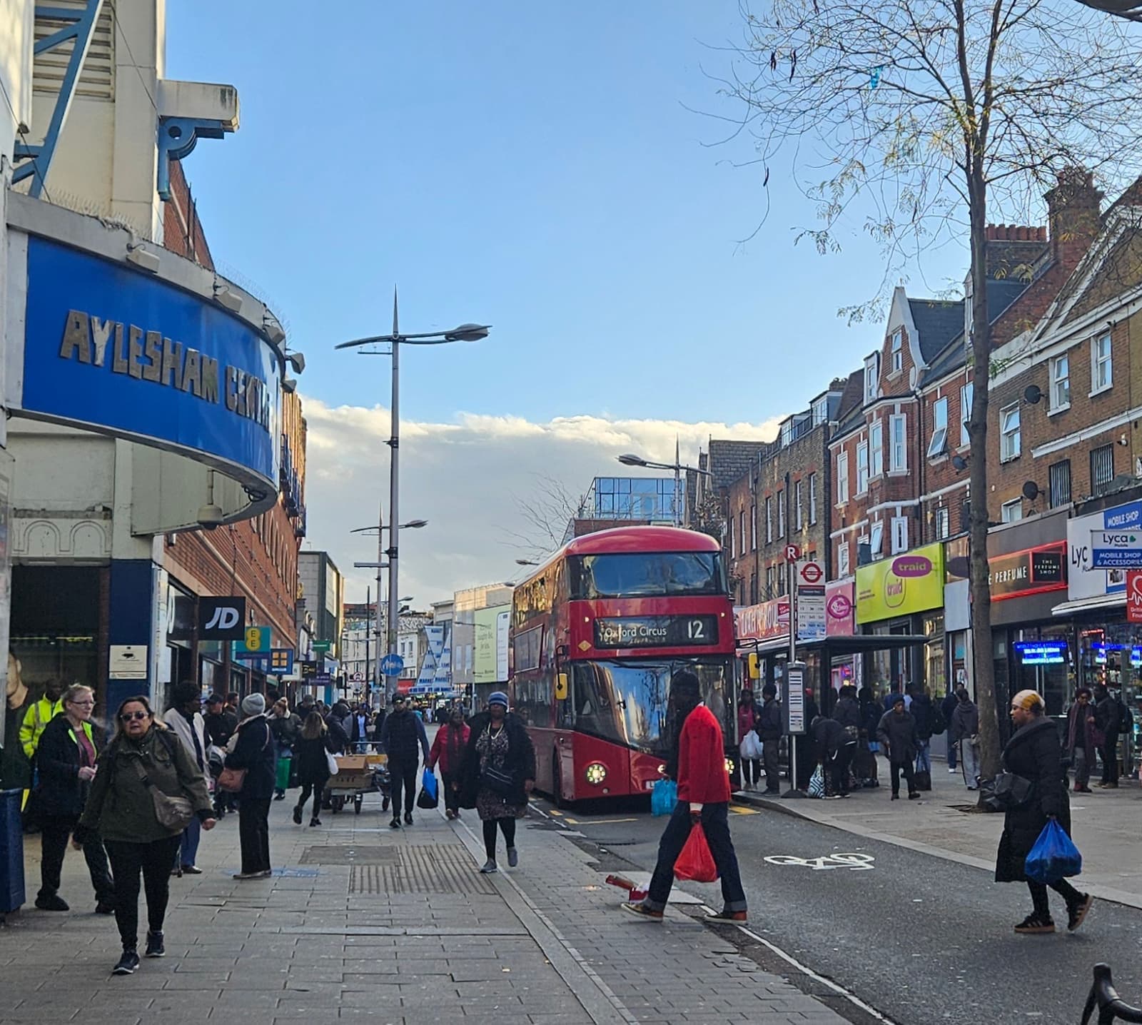 A busy high street with a red double-decker bus and shoppers