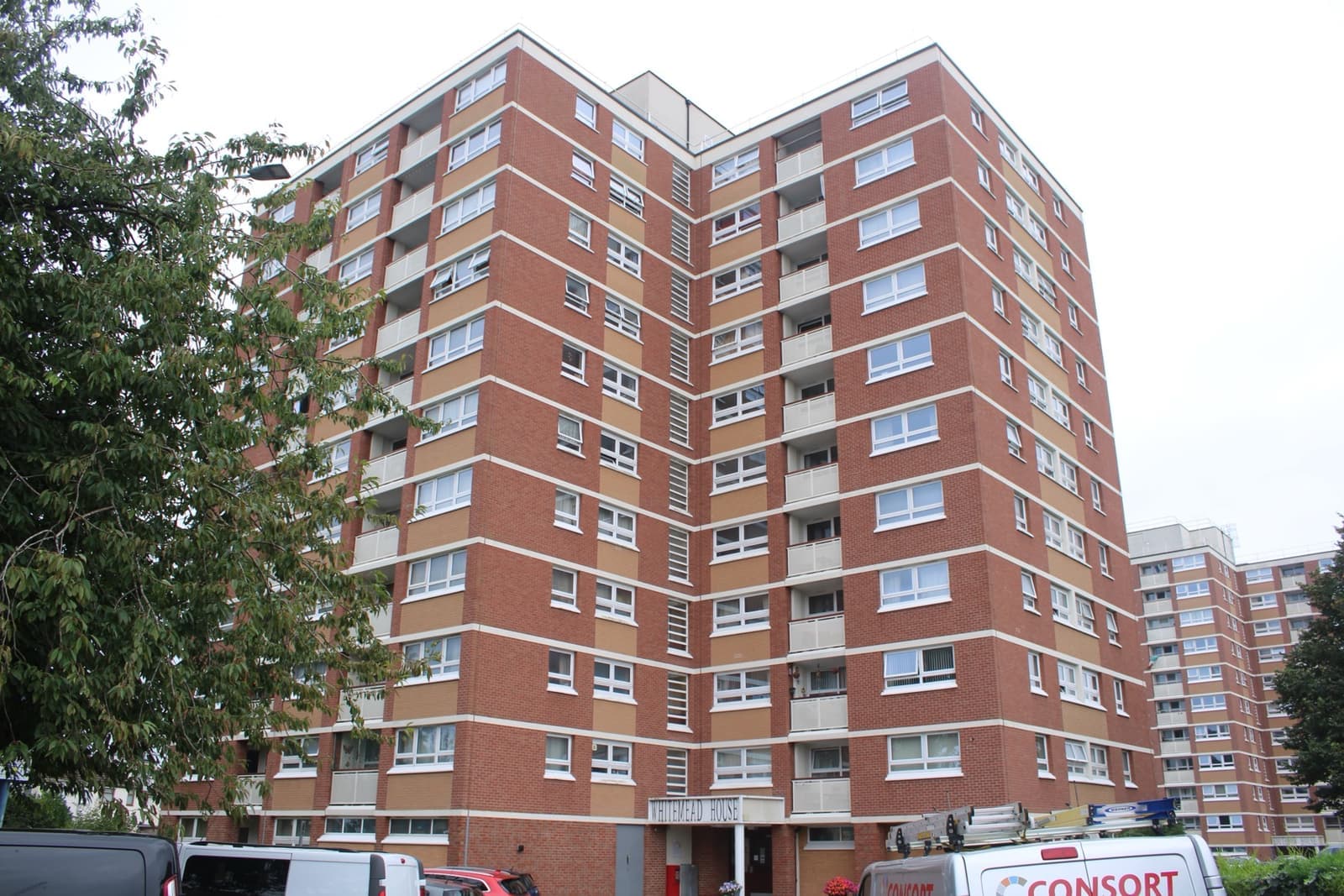 A tall red-brick tower block of flats against a white sky