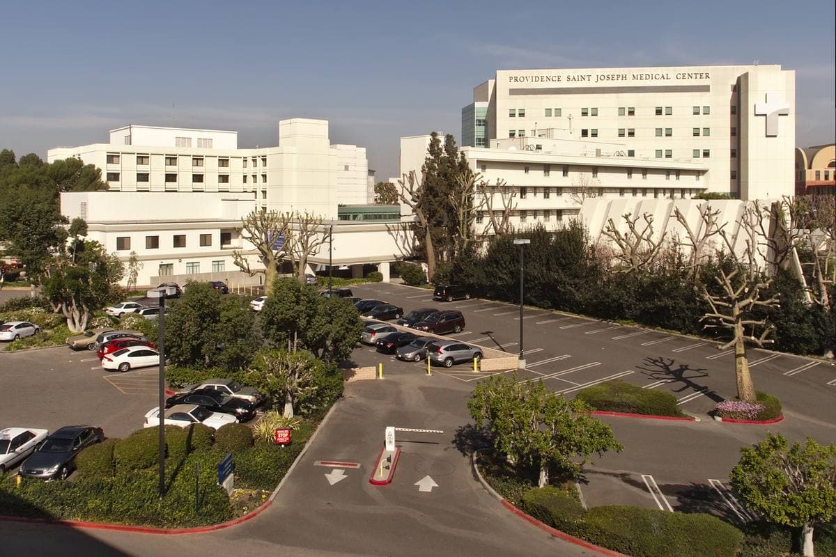 White hospital buildings above a landscaped car park