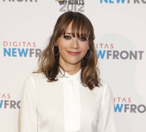 Rashida Jones with a fringe and hoop earrings, in a white blouse