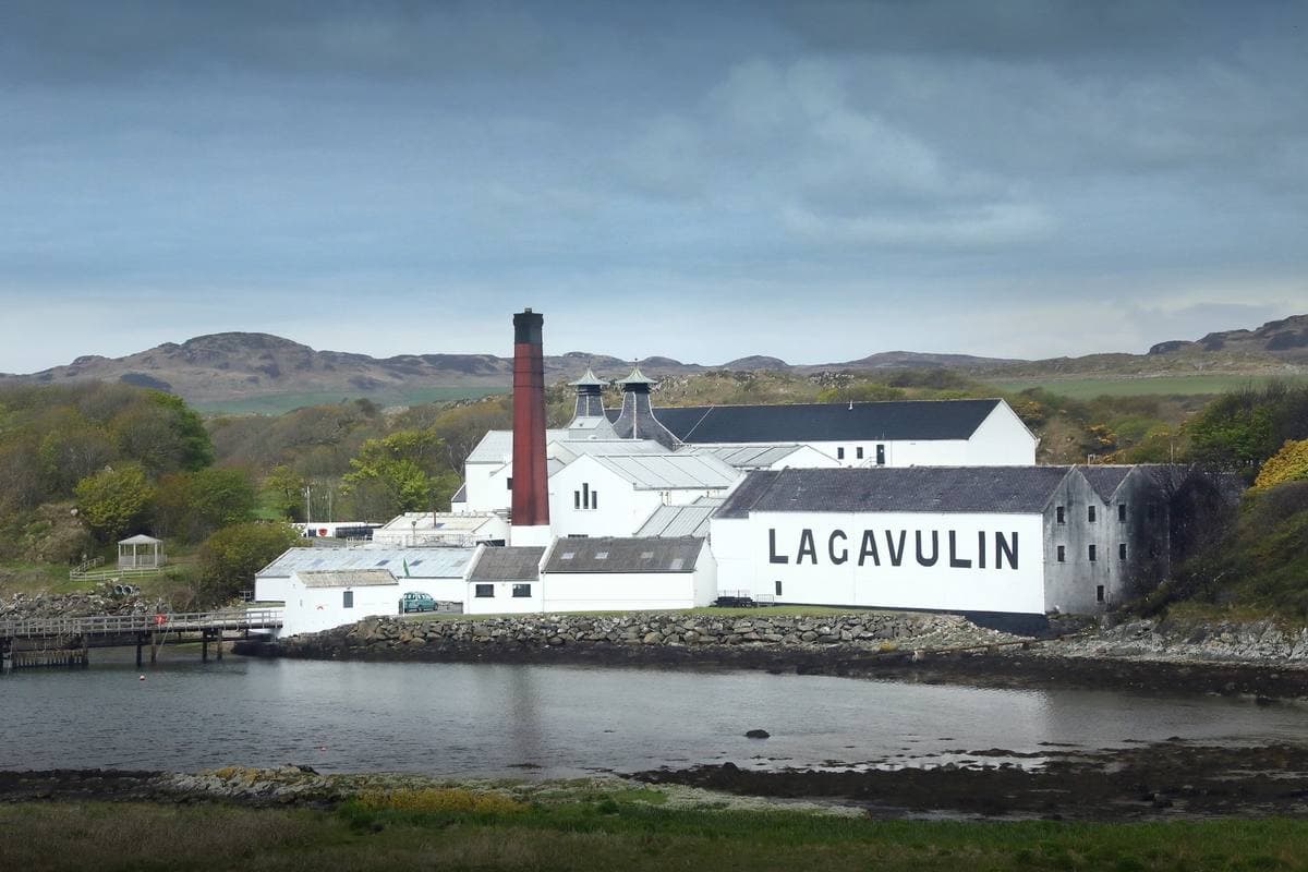 White distillery buildings with LAGAVULIN painted on the wall, beside a bay