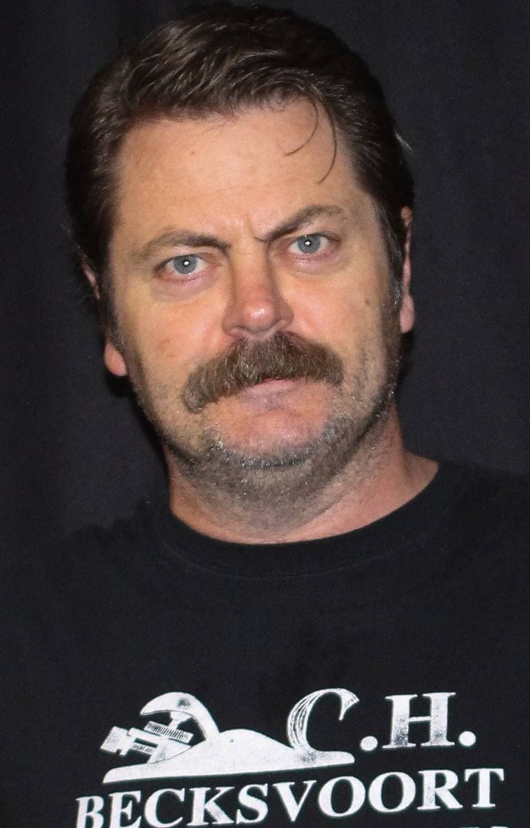 Nick Offerman with a thick moustache and swept-back hair, looking straight at the camera