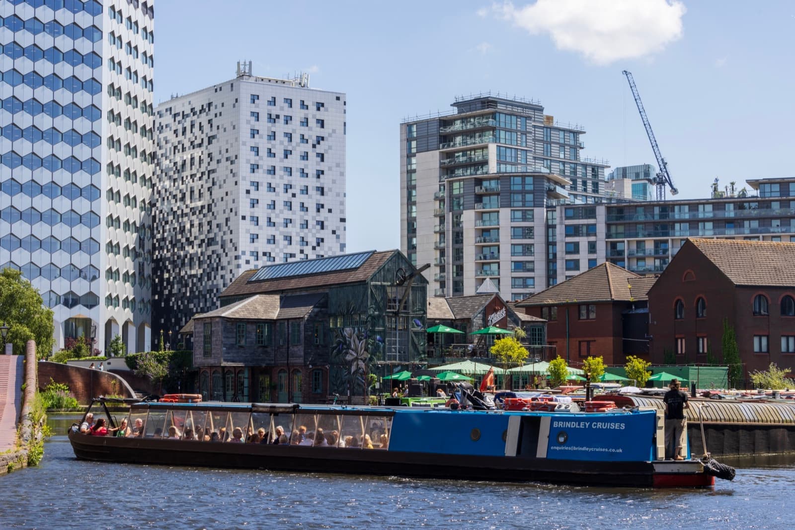 Narrowboats moored in a canal basin below modern towers