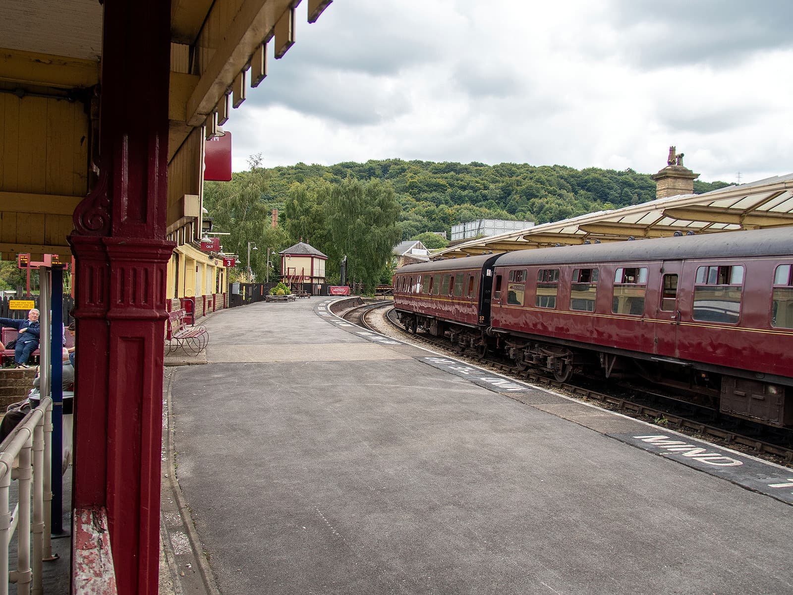A maroon heritage train beside a canopied station platform