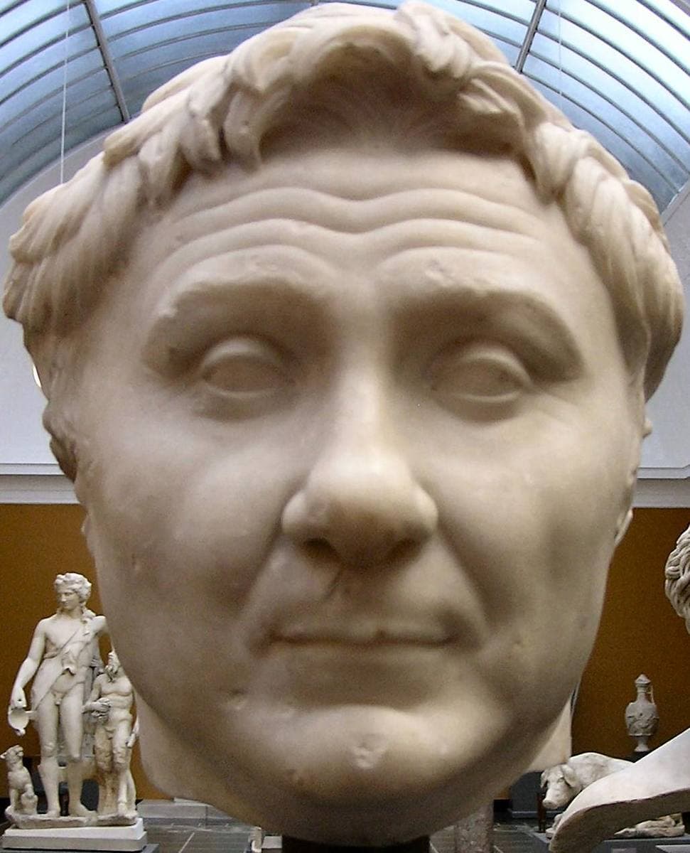 A marble head of a broad-faced man with a lock of hair raised over the forehead
