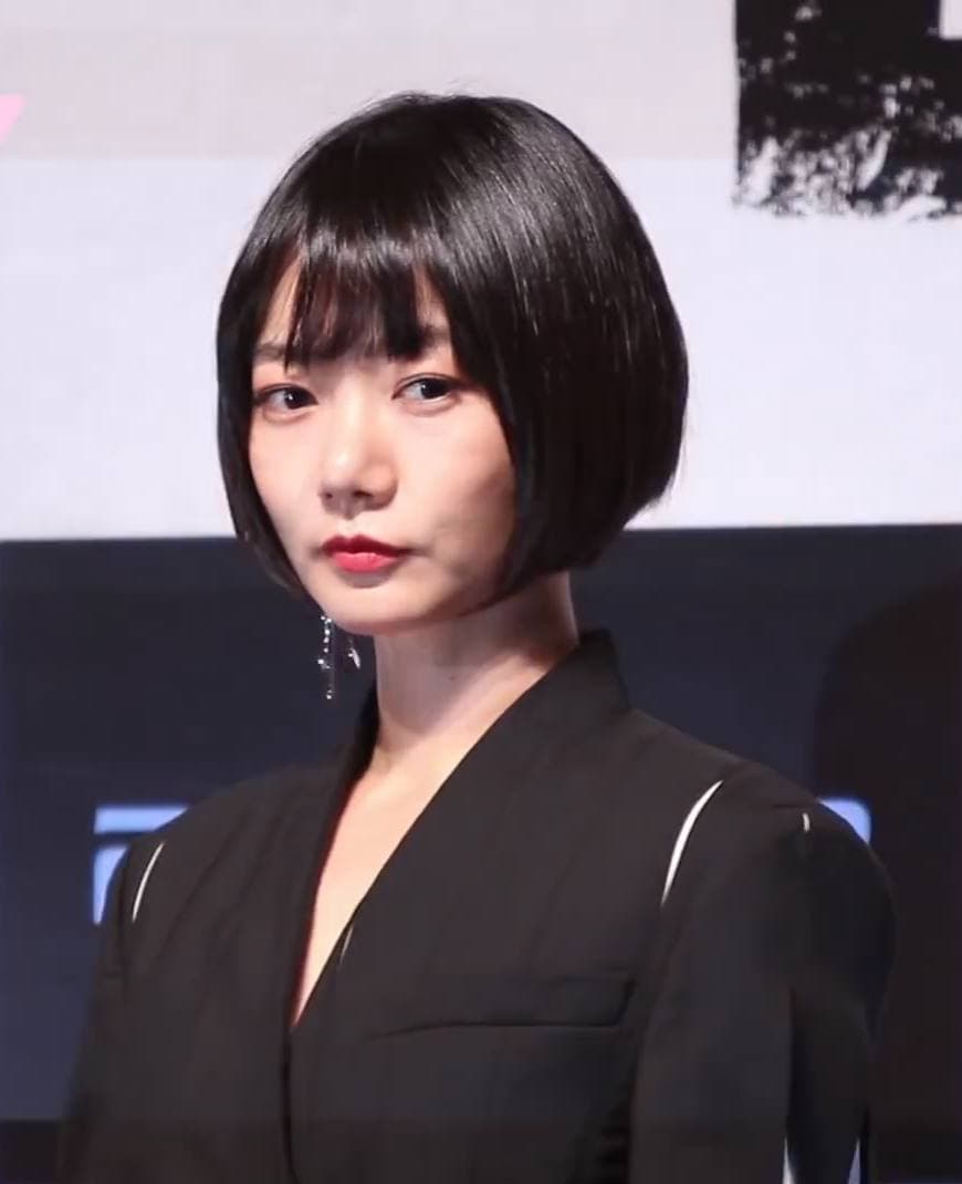 Doona Bae with a black bob and a black jacket, looking at the camera