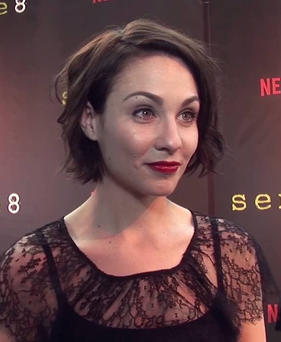 Tuppence Middleton in black lace, smiling, in front of a backdrop with the show's name