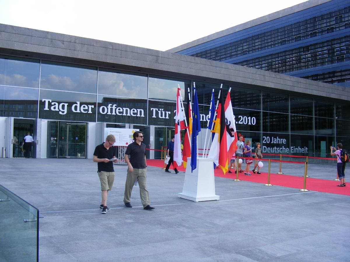 A modern glass office front with flags and a red carpet at the entrance