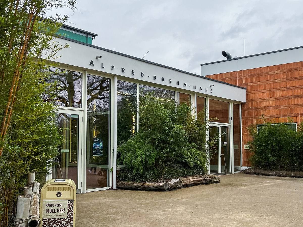 A long low glass-fronted zoo building with its name along the roofline