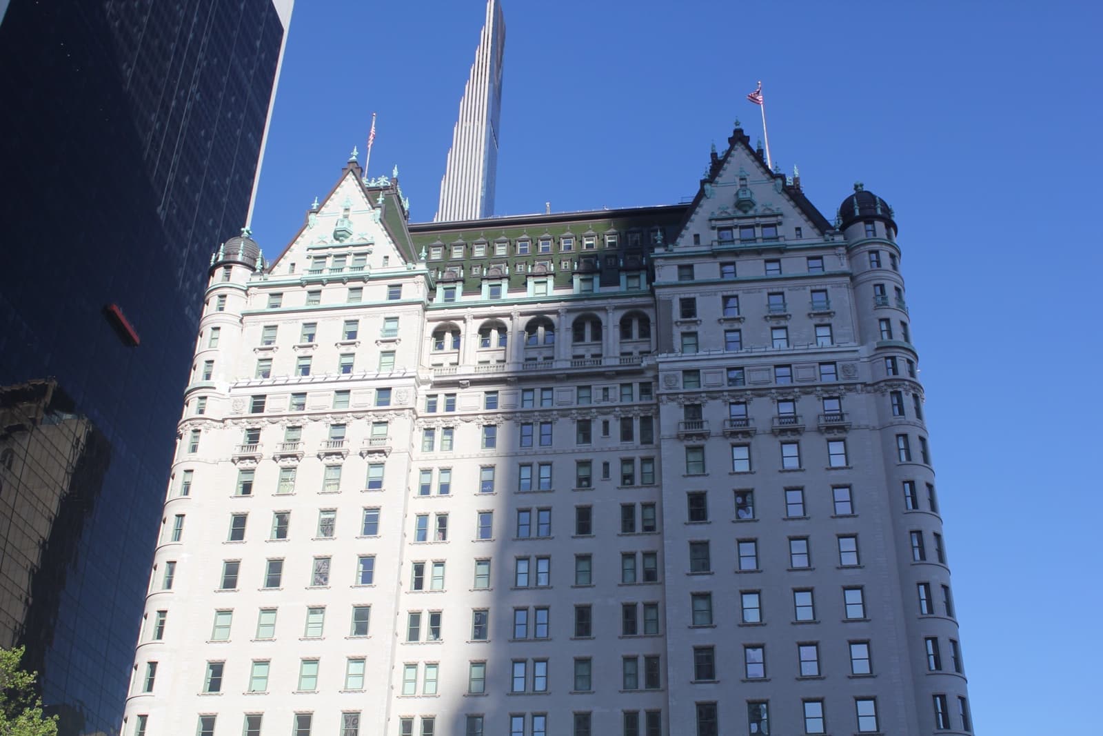 A tall white château-style hotel with green copper roofs against a blue sky
