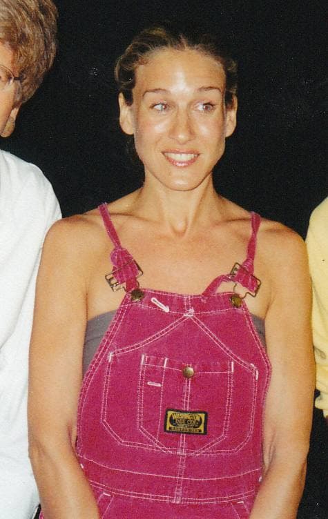 Sarah Jessica Parker, hair scraped back, smiling, in pink dungarees