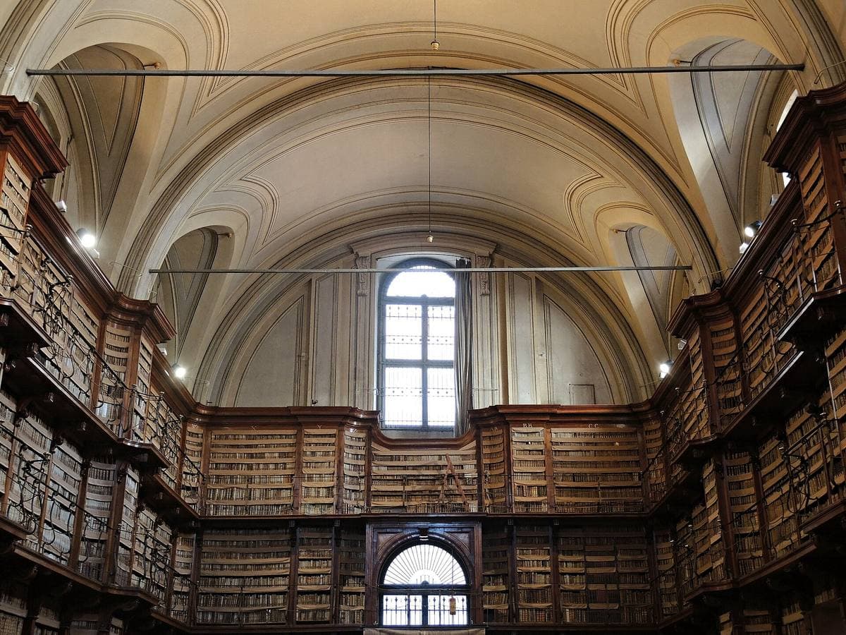 A tall hall lined with wooden bookcases and a gallery