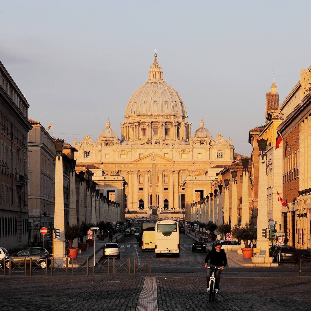 A straight avenue with lamp-posts leading to the dome of St Peter’s