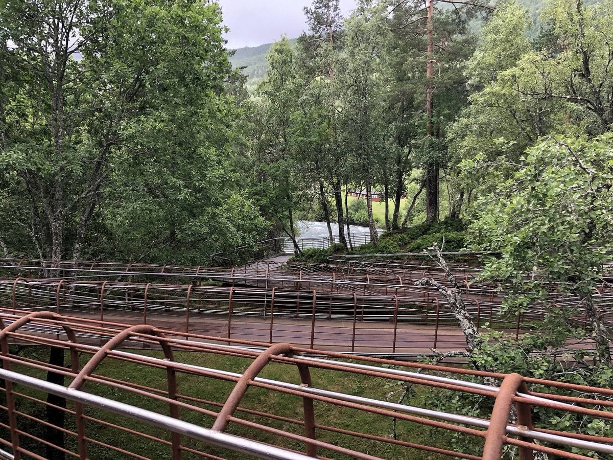Rust-red steel walkways curving through birch woods above a gorge