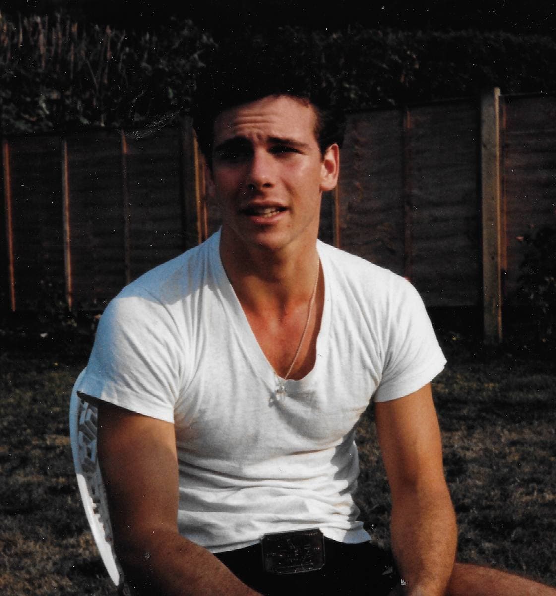 Marcus D’Amico in a white T-shirt, sitting outdoors