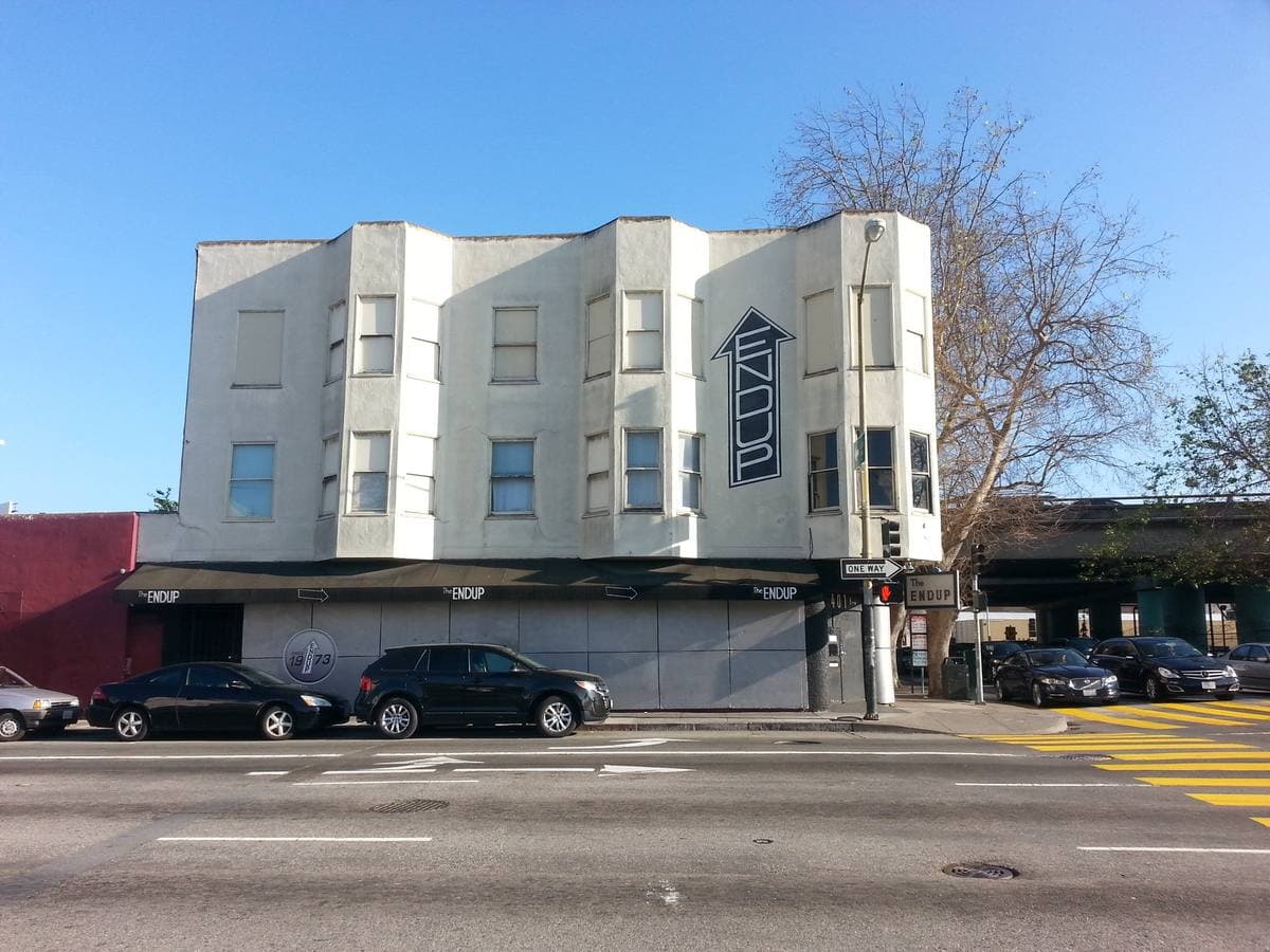 A white two-storey corner building with a vertical sign