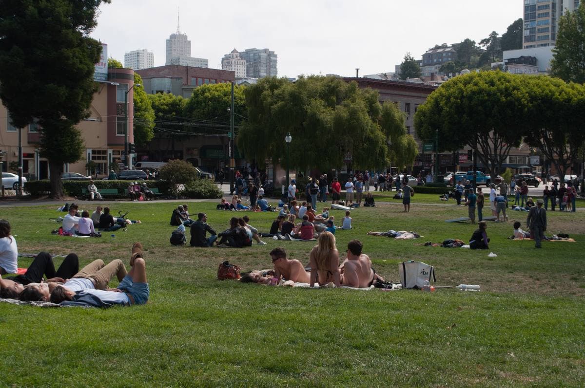 People on the lawn of Washington Square with the church towers behind