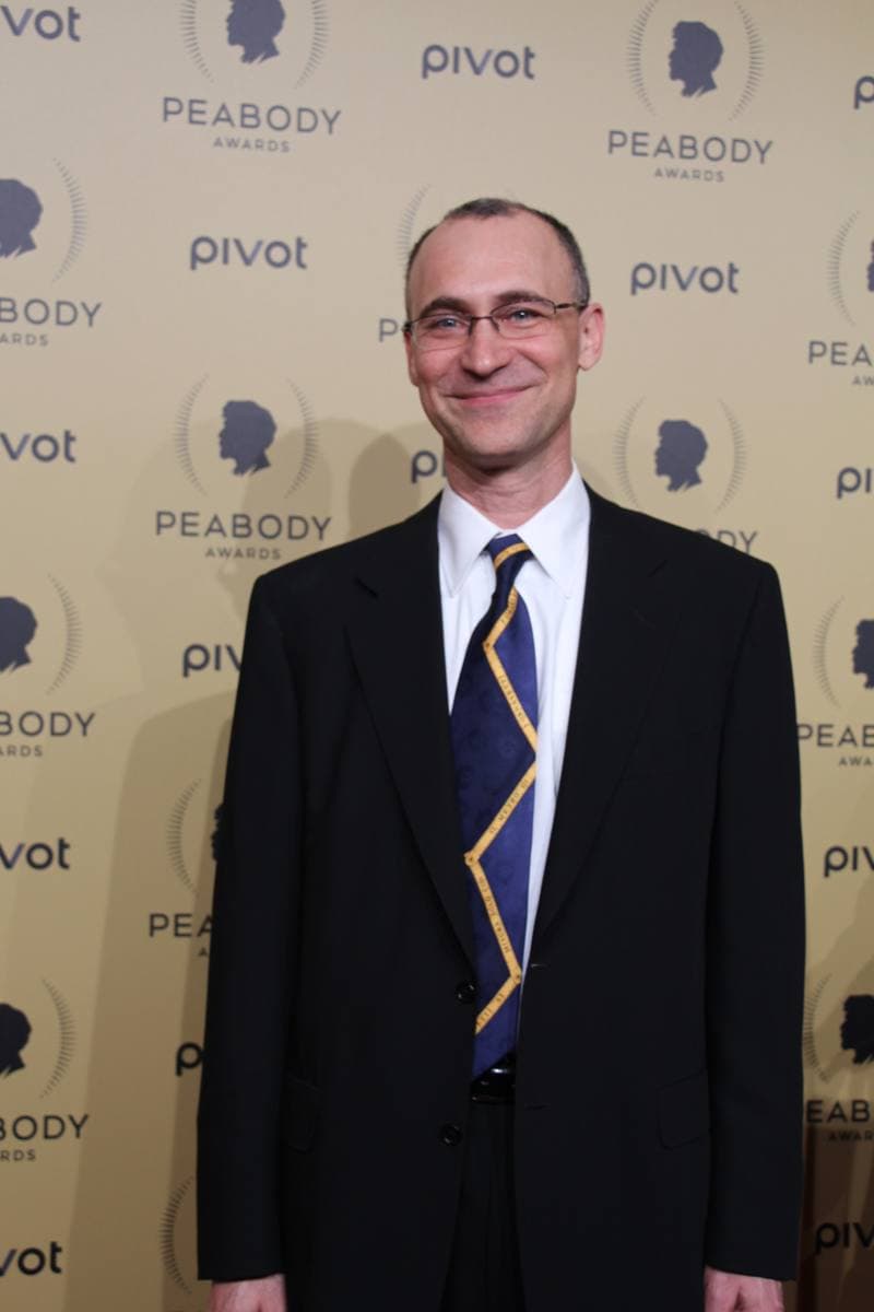 Joel Fields in a dark suit on a red carpet
