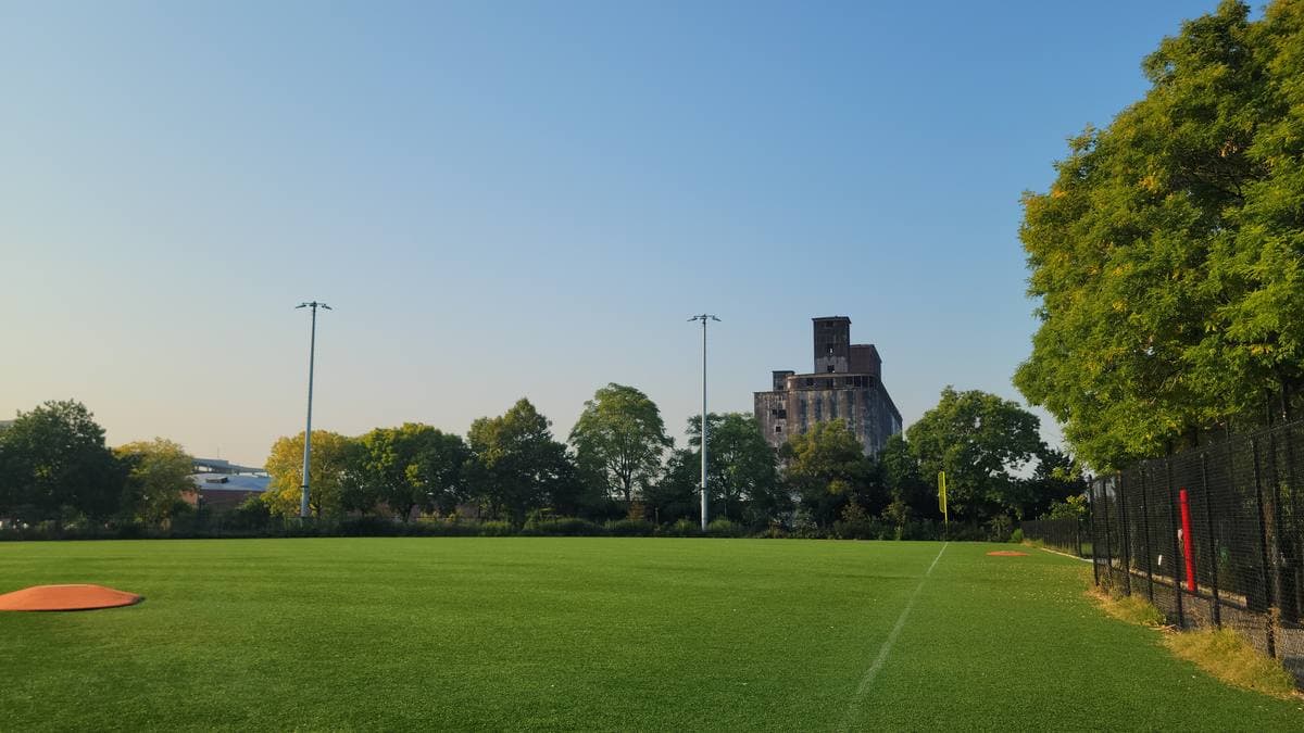 A baseball field with a tall concrete grain terminal behind it