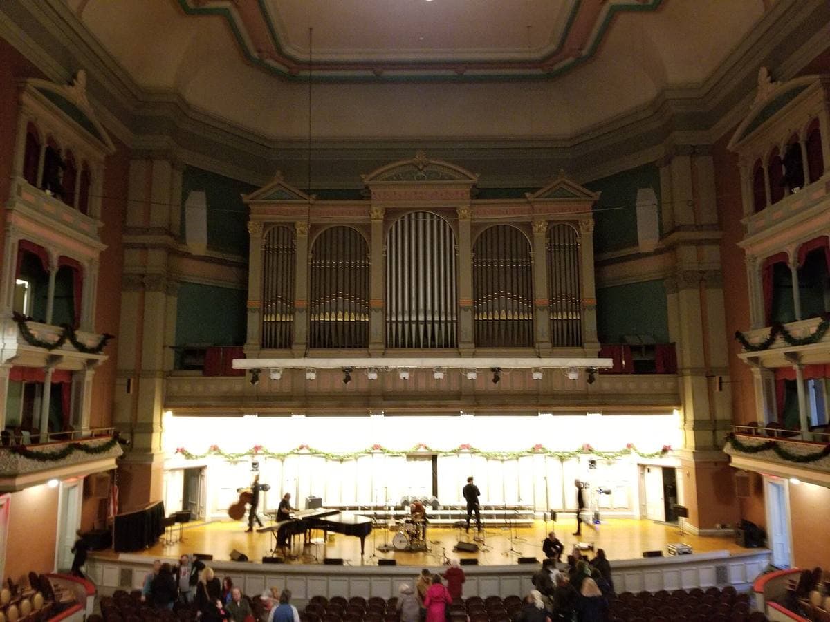 A concert hall stage with a tall carved wooden organ case behind it