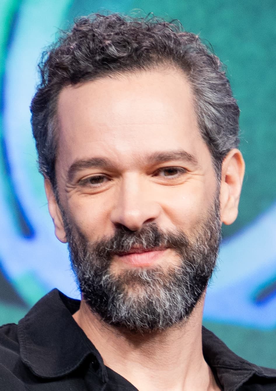 Neil Druckmann, bearded, smiling on stage