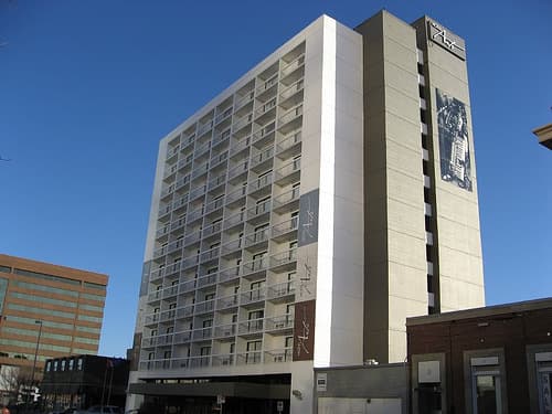 A pale modern hotel tower against a deep blue sky
