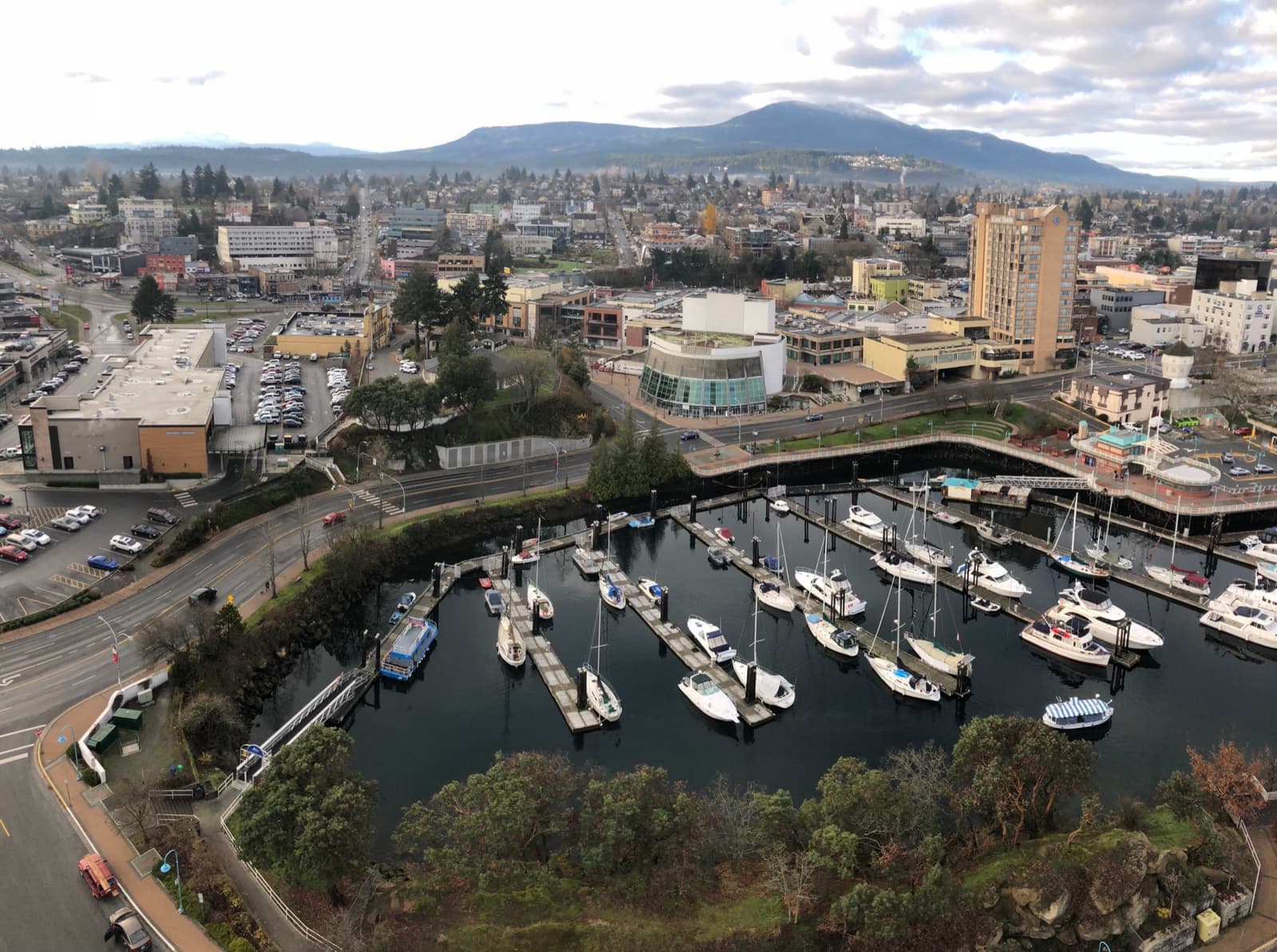Downtown Nanaimo seen from above, a harbour of moored boats in front and hills behind