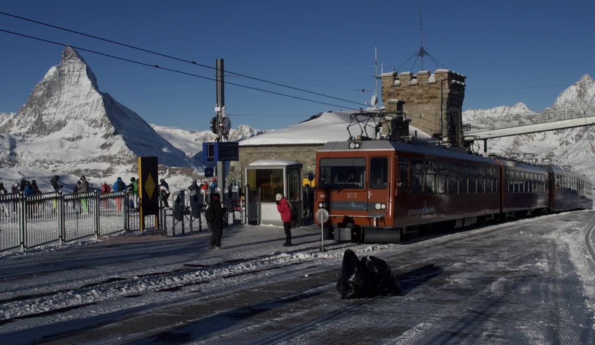 Two red rack-railway trains in deep snow at a mountain station