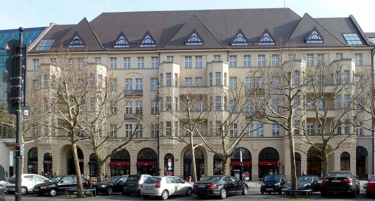 A long, grand stone building on a tree-lined boulevard