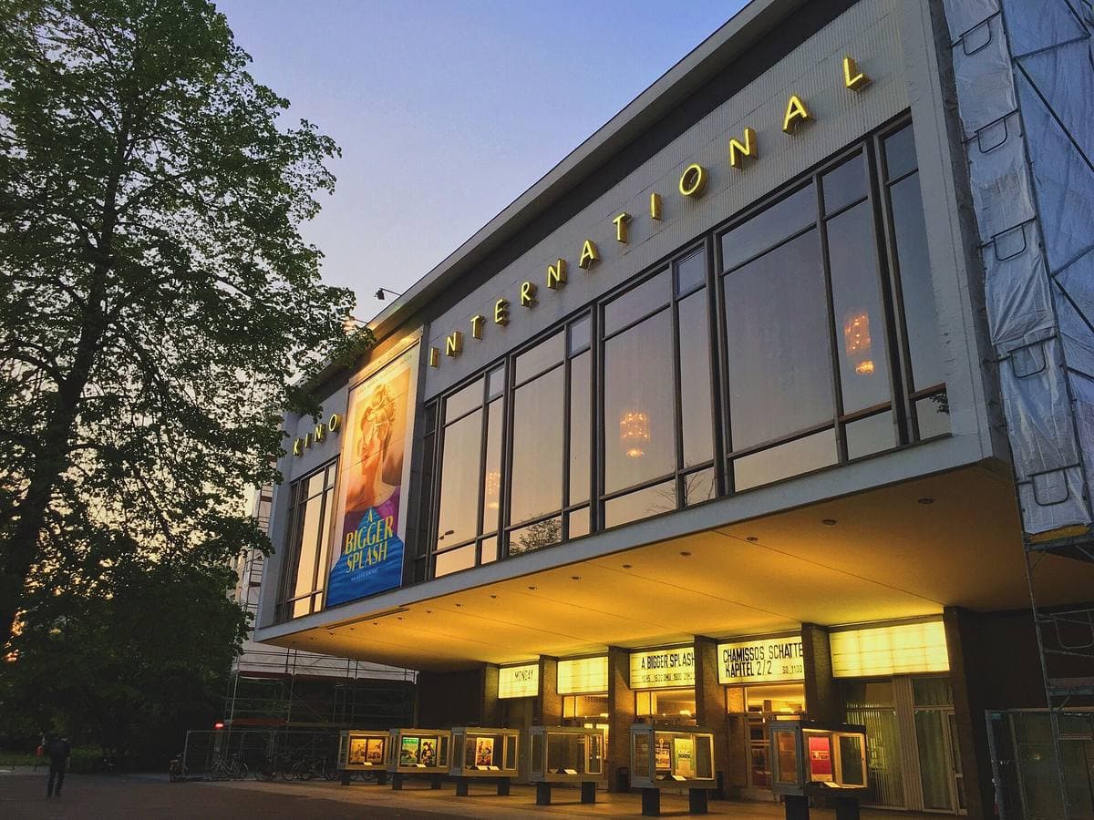 A low glass-fronted modernist cinema with its name in lights at dusk