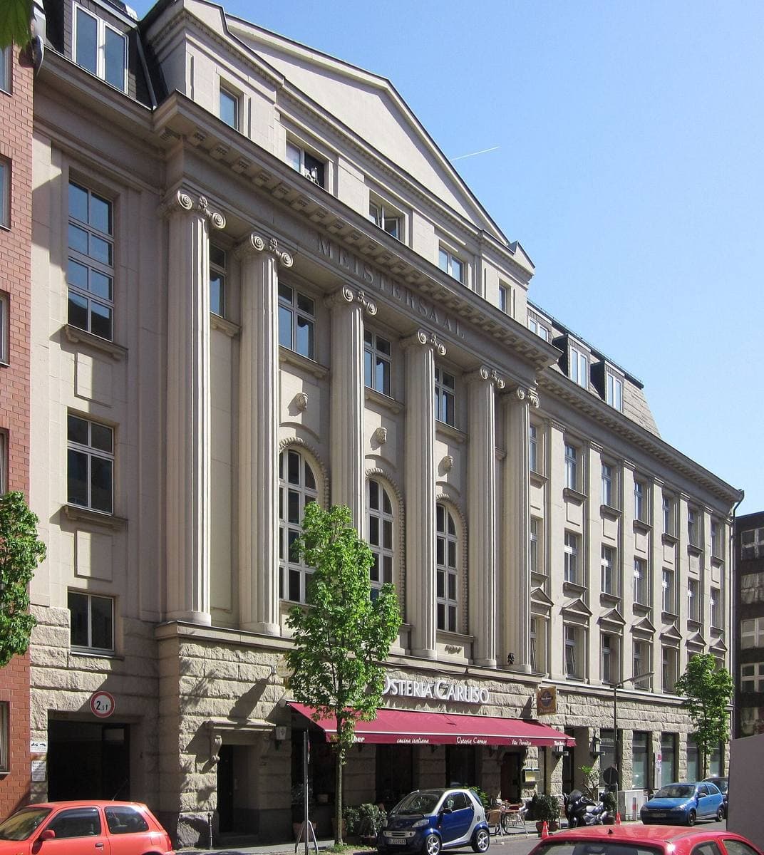A tall stone facade with arched windows on a city street