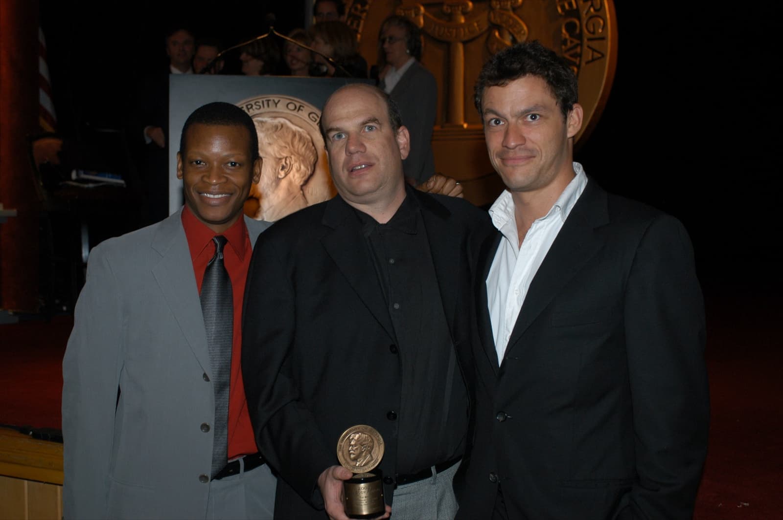 Lawrence Gilliard Jr., David Simon and Dominic West on stage, one holding a Peabody medal