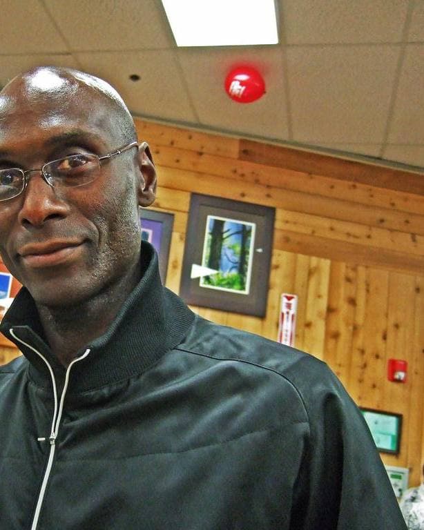 Lance Reddick in glasses and a black zip jacket