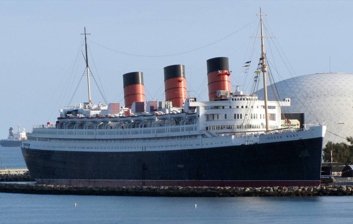 The Queen Mary ocean liner, with three red funnels, moored at Long Beach