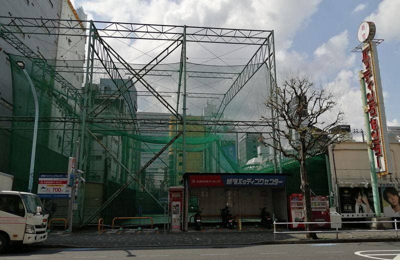 Tall green nets over a batting cage beside a street