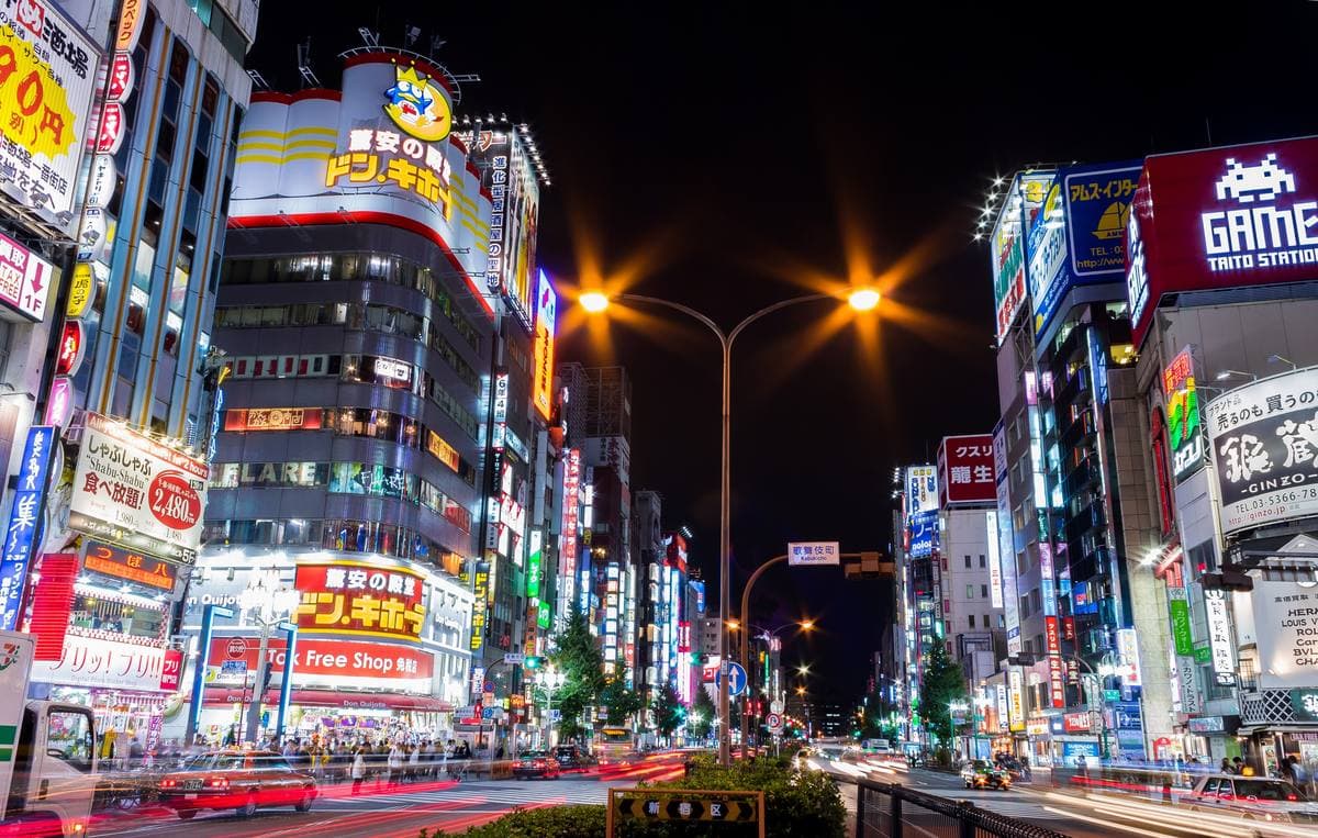 A wide street at night lined with lit signs and towers