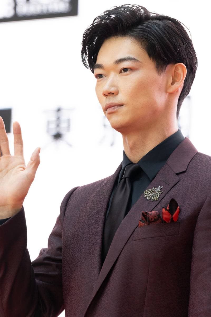 Show Kasamatsu in a burgundy jacket, raising a hand