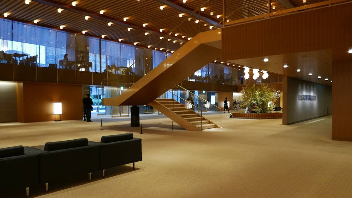 A long low hotel lobby with wood panelling, lantern lights and black chairs